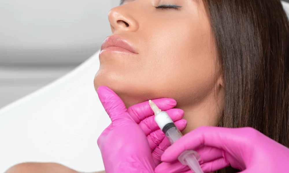 Woman receiving a Kybella chin injection from a professional in pink gloves in Carmel IN